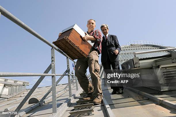 Apiculteur Nicolas Geant transporte une ruche à côté du président du Grand Palais Yves Saint-Geours, le 07 mai 2009 sur les toits du Grand Palais à...