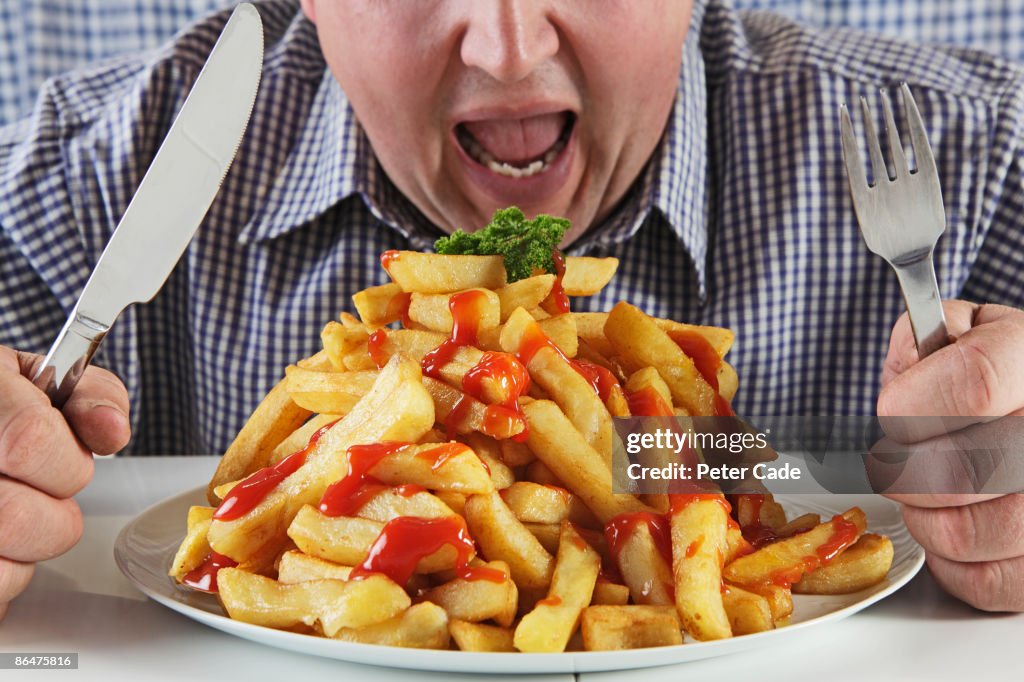 Man eating very large plate of fries