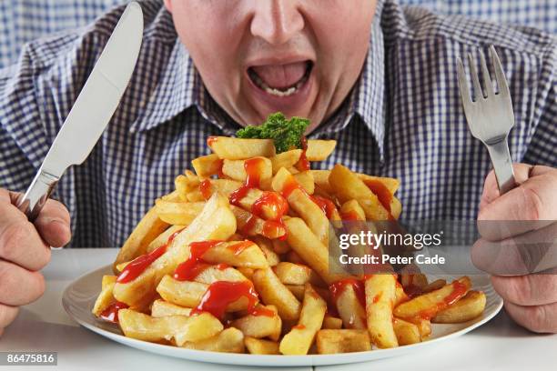 man eating very large plate of fries - carbohidrato fotografías e imágenes de stock