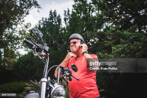 a senior man getting on a motorcycle. - motorcycle travel stock-fotos und bilder