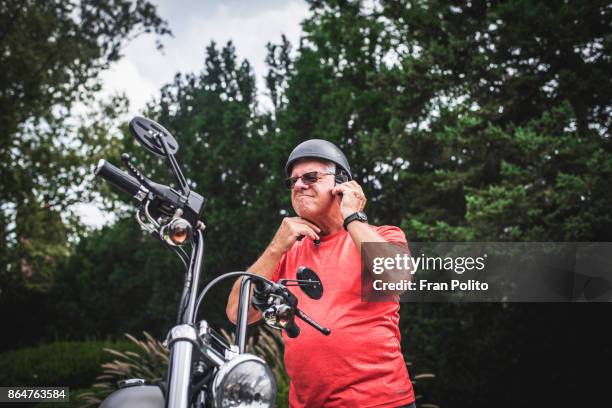 A senior man getting on a motorcycle.