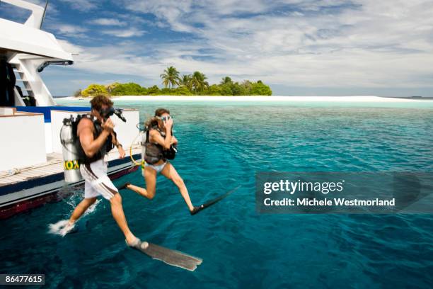 divers jumping into ocean, maldives - sporttauchen stock-fotos und bilder