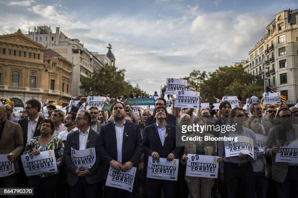 Carles Puigdemont, Catalonia's president, center, holds a sign that reads "Free The Jordis," during a demonstration against the Spanish government...