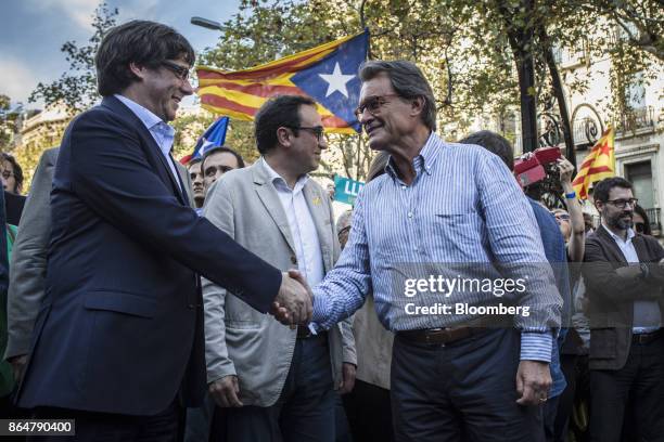 Carles Puigdemont, Catalonia's president, left, shakes hands with Artur Mas, former Catalan president, during a demonstration against the Spanish...