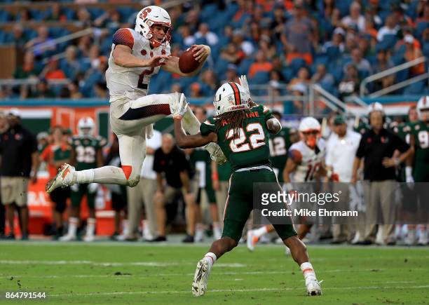 Eric Dungey of the Syracuse Orange tries to jump over Sheldrick Redwine of the Miami Hurricanes during a game at Sun Life Stadium on October 21, 2017...