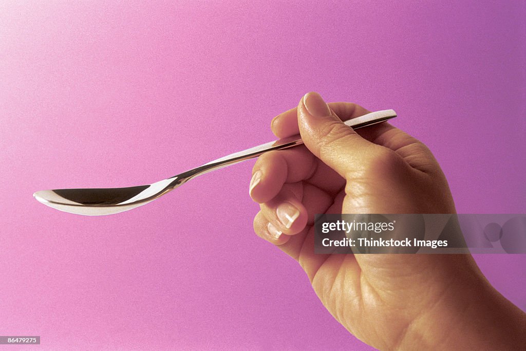 Hand holding teaspoon