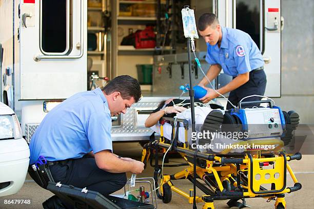 paramedics loading patient into ambulance - paramedics stock pictures, royalty-free photos & images