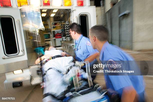 paramedics loading patient into ambulance - stretcher stock-fotos und bilder