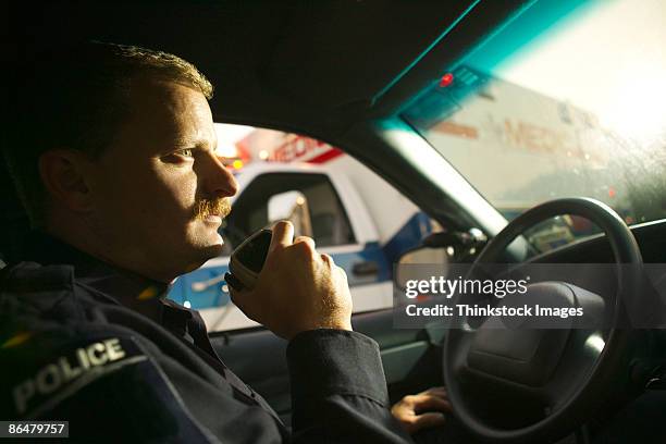 police officer using radio in car - police officer sitting in a police car stock pictures, royalty-free photos & images