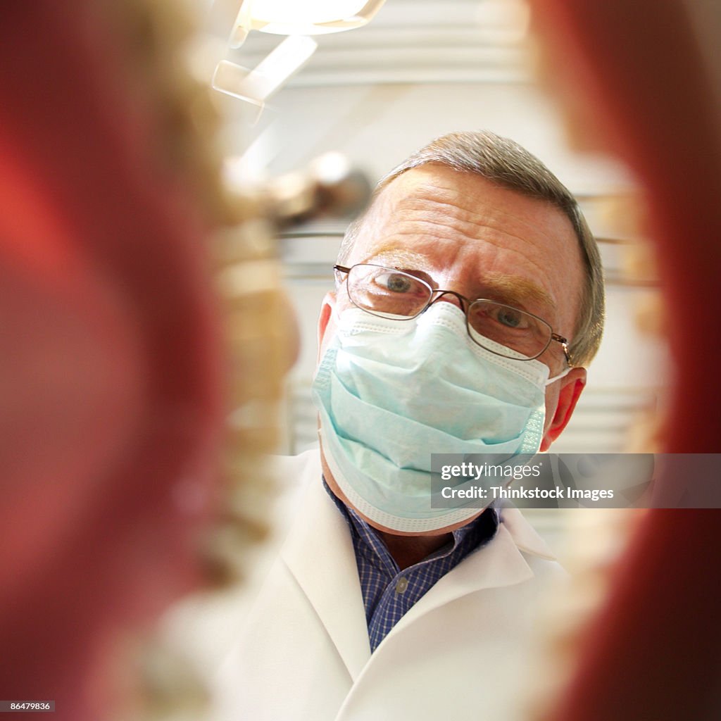 Dentist over open mouth with drill