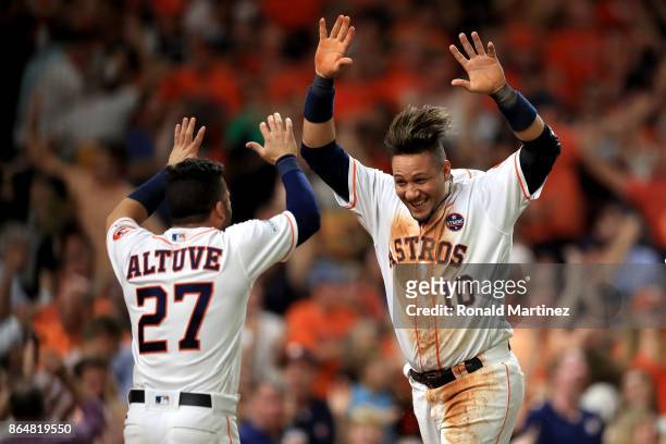 Yuli Gurriel of the Houston Astros celebrates with teammate Jose Altuve after scoring off of a double hit by Brian McCann against Tommy Kahnle of the...