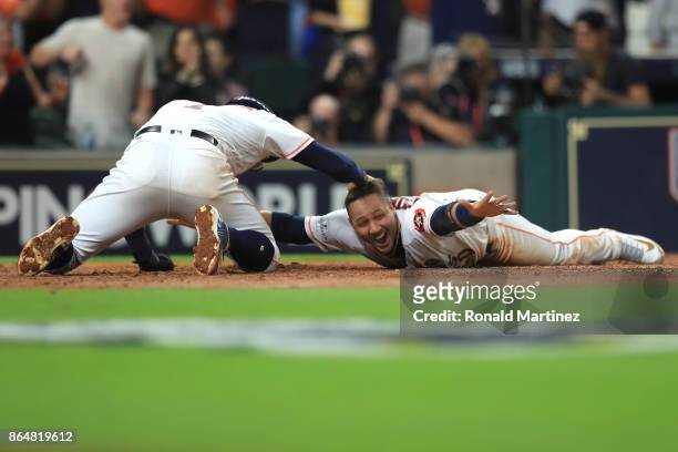 Yuli Gurriel of the Houston Astros celebrates with teammate Carlos Correa after scoring off of a double hit by Brian McCann against Tommy Kahnle of...