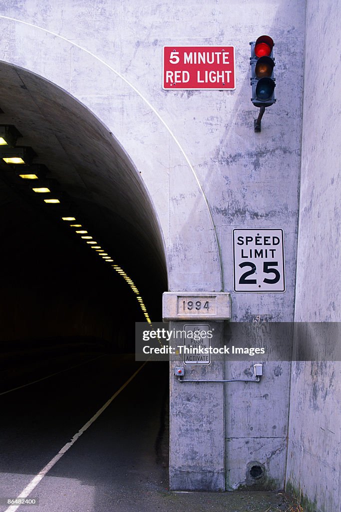 Tunnel entrance with road signs and traffic light