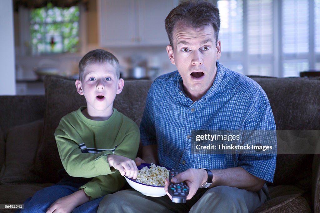 Father and son with remote control and popcorn