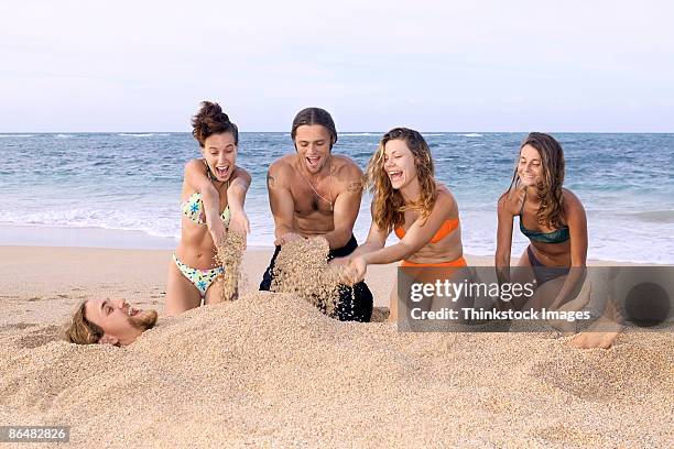 people burying man in sand - bury fotografías e imágenes de stock