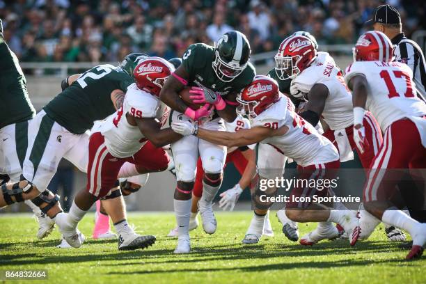 Spartans running back L.J. Scott fights through the tackle of Hoosiers defensive end Allen Stallings IV and safety Chase Dutra during a Big Ten...