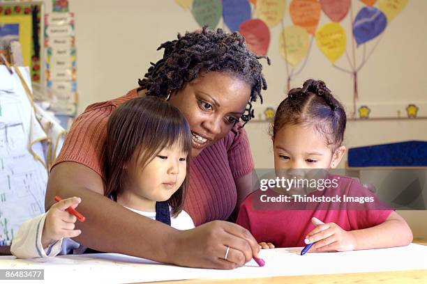 teacher coloring with girls - daycare foto e immagini stock