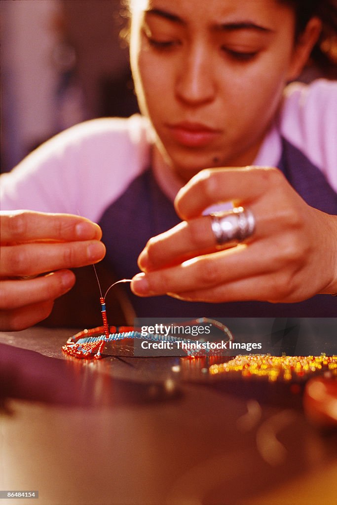 Teenage girl making beaded jewelry