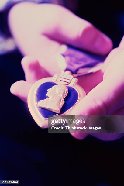 hands holding purple heart medal - purple-heart stockfoto's en -beelden