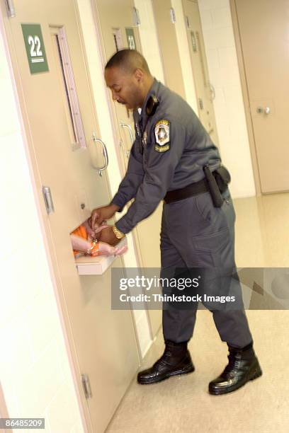 corrections officer handcuffing inmate in cell - prison guard - fotografias e filmes do acervo