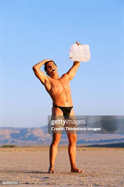 man in desert pouring water on himself - string stockfoto's en -beelden