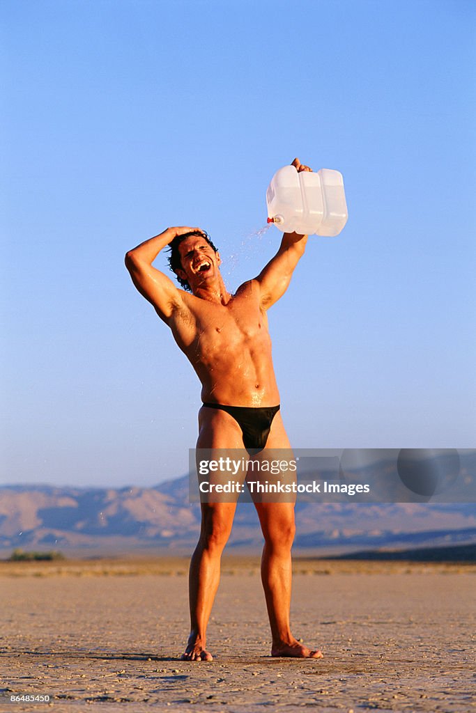 Man in desert pouring water on himself