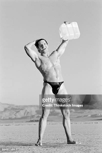 man in desert pouring water from jug on himself - string stockfoto's en -beelden
