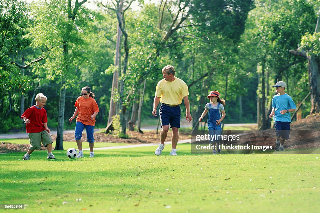 Father playing soccer with kids