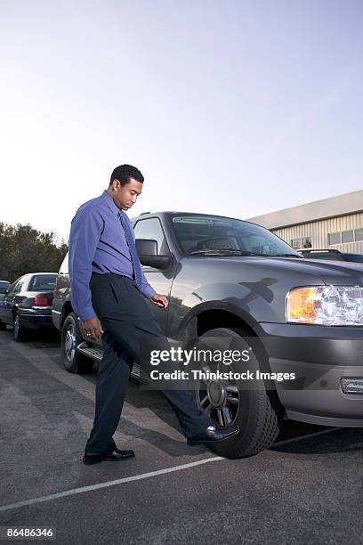 man kicking car tire - kicking tire stock pictures, royalty-free photos & images