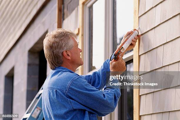 man caulking window - caulk stock pictures, royalty-free photos & images