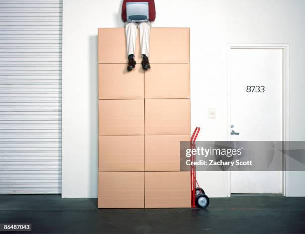 man sits atop large stack of boxes on dolly - top of cardboard box stock pictures, royalty-free photos & images