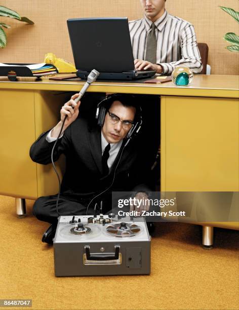 spy recording a man typing at desk - espiar una conversación fotografías e imágenes de stock