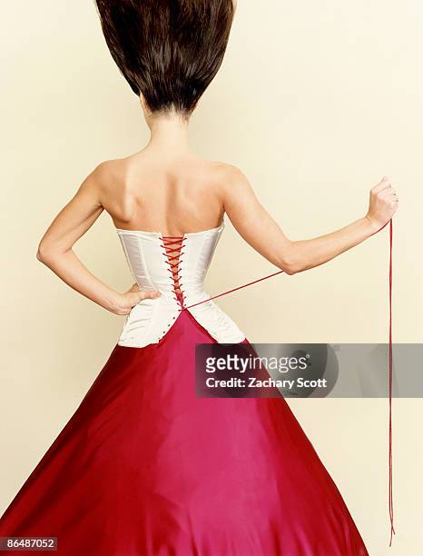 woman pulls corset tight around waist - vintage corset stock-fotos und bilder