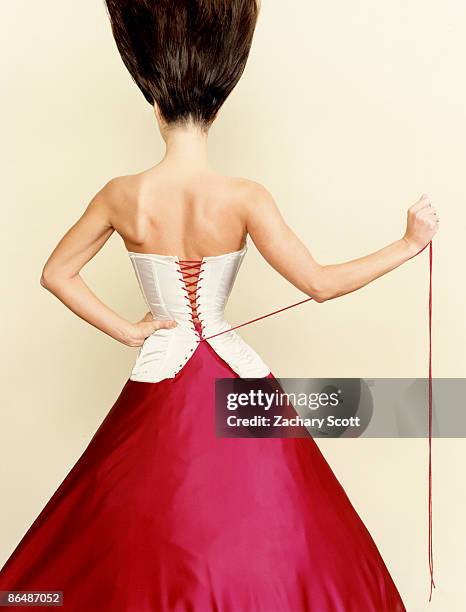 woman pulls corset tight around waist - corset stock pictures, royalty-free photos & images