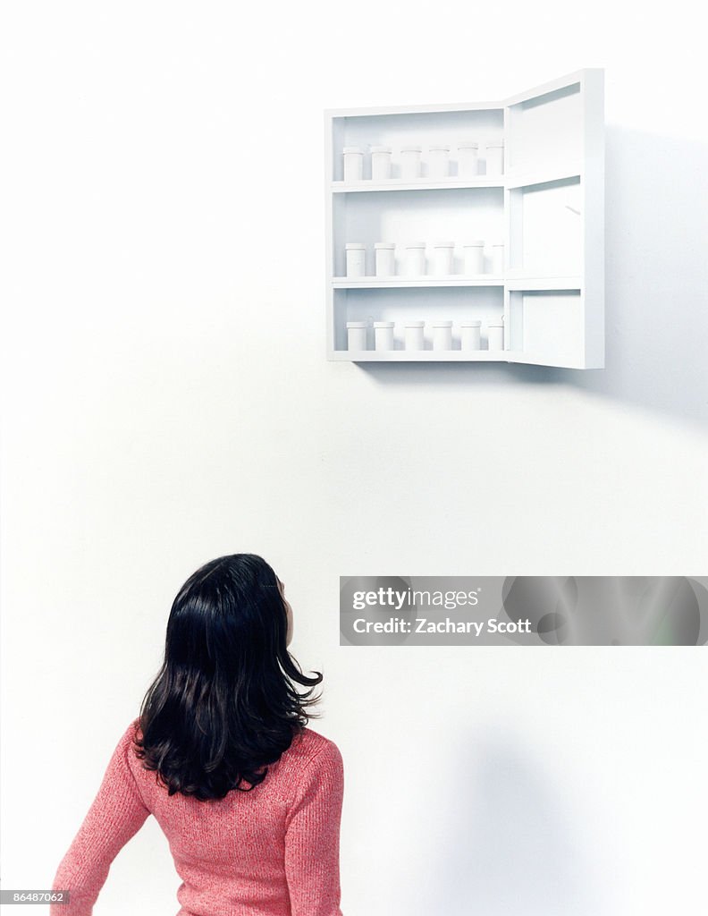 Woman looks at out of reach medicine cabinet