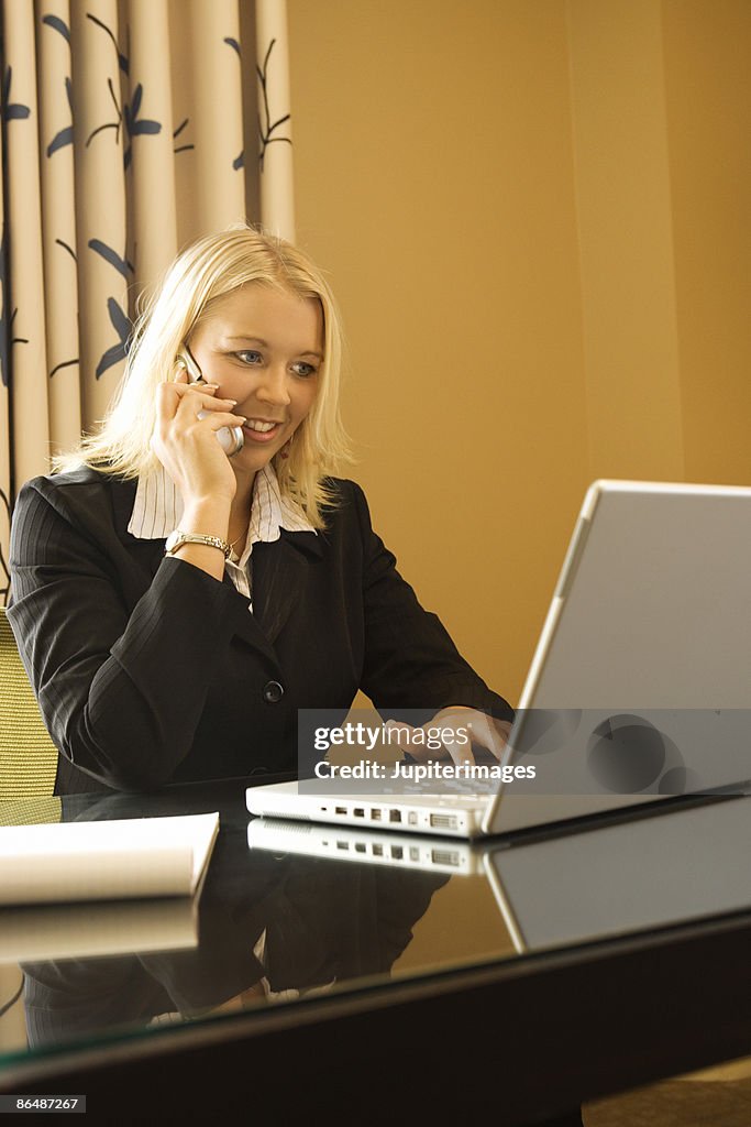 Businesswoman using laptop and cell phone