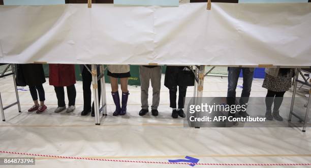 Japanese voters fill in their ballot papers at a polling station to vote in Japan's general election in Tokyo on october 22, 2017. Polls opened in...