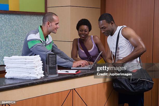 gym employee helping couple at front desk - gym receptionist stock pictures, royalty-free photos & images