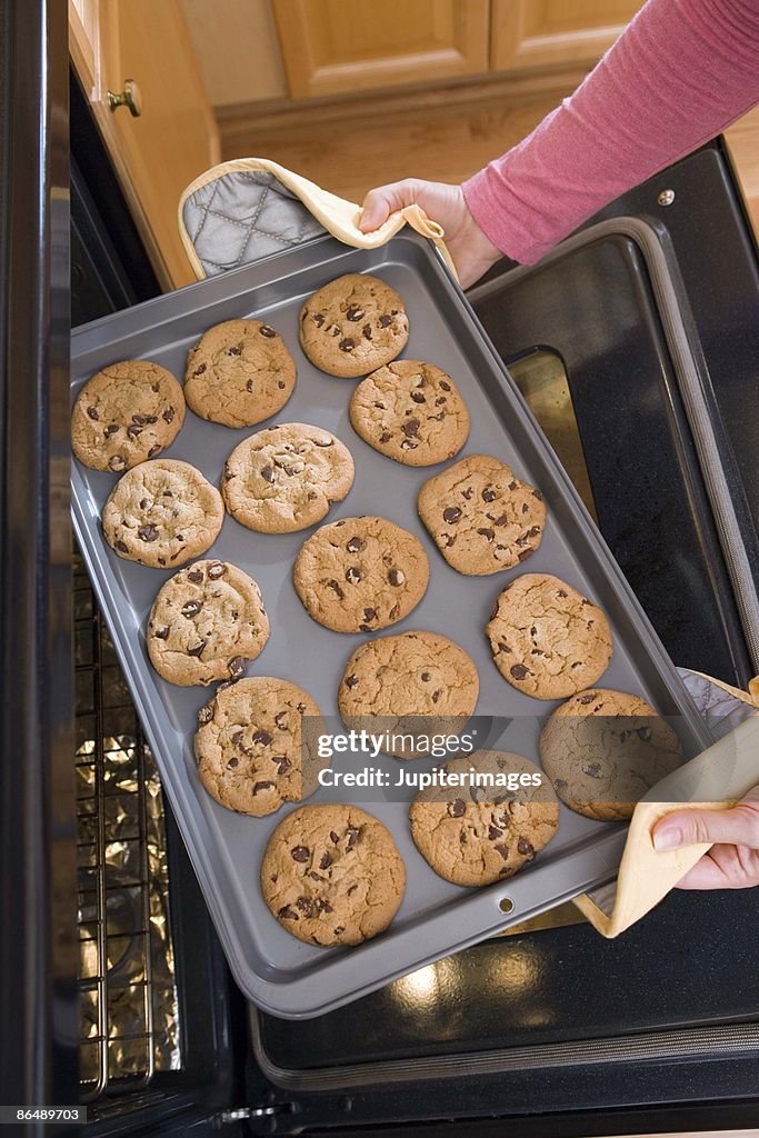 Woman removing cookies from oven