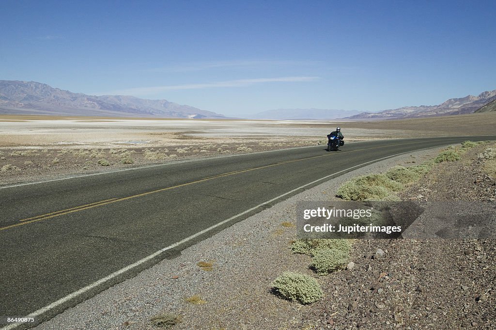 Desert highway with motorcyclist
