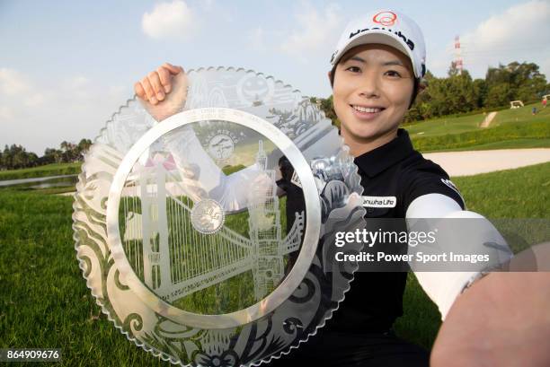 Eun-Hee Ji of South Korea pretends to take a selfie while holding the trophy on the 18th green after winning the Swinging Skirts LPGA Taiwan...
