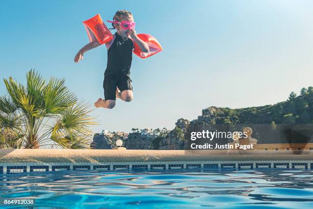 young girl jumping into pool - young girl jumping into swimming pool stock pictures, royalty-free photos & images