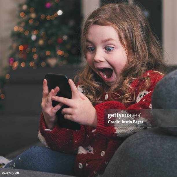 excited girl using smartphone at xmas - christmas jumper stock pictures, royalty-free photos & images