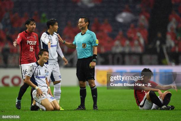 Referee Hajime Matsuo prepares to show an yellow card to Koki Yonekura of Gamba Osaka during the J.League J1 match between Urawa Red Diamonds and...