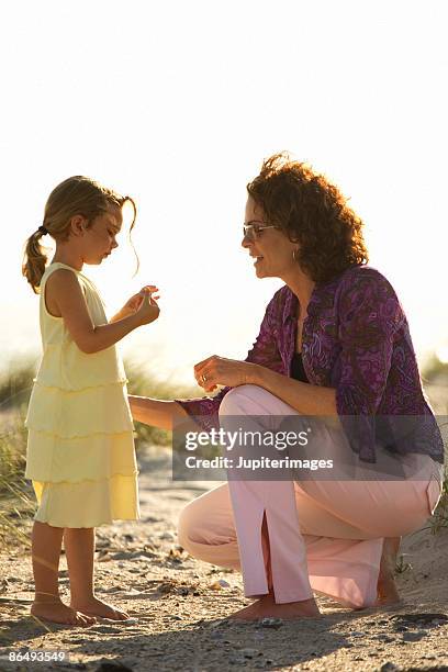mother and daughter collecting seashells - family gathering seashells on beach stock pictures, royalty-free photos & images