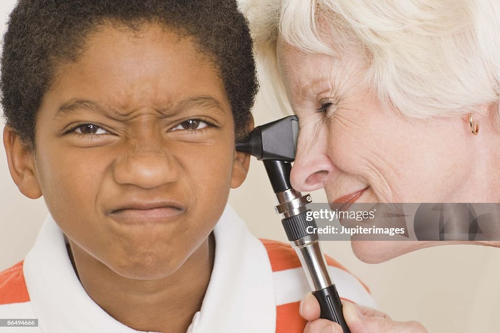 Doctor examining grimacing boy