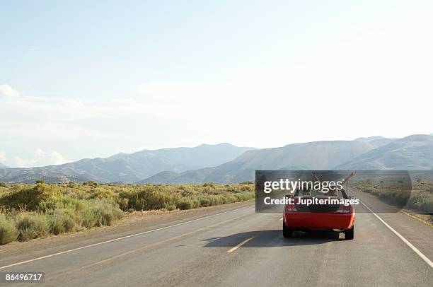 carefree couple driving convertible on desert road - convertible stockfoto's en -beelden