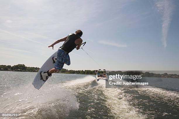 midair wakeboarder and boat - wakeboarden stock-fotos und bilder