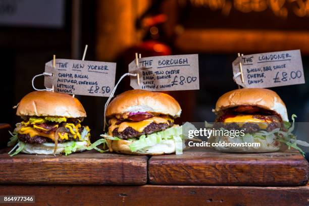 freshly flame grilled burgers displayed in a row at borough market, london - borough market stock pictures, royalty-free photos & images