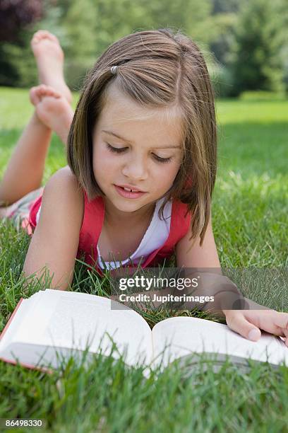 girl lying down and reading book in grass - fille lire gazon photos et images de collection